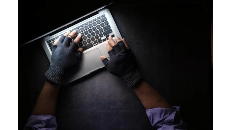 guy with fingerless gloves typing on computer