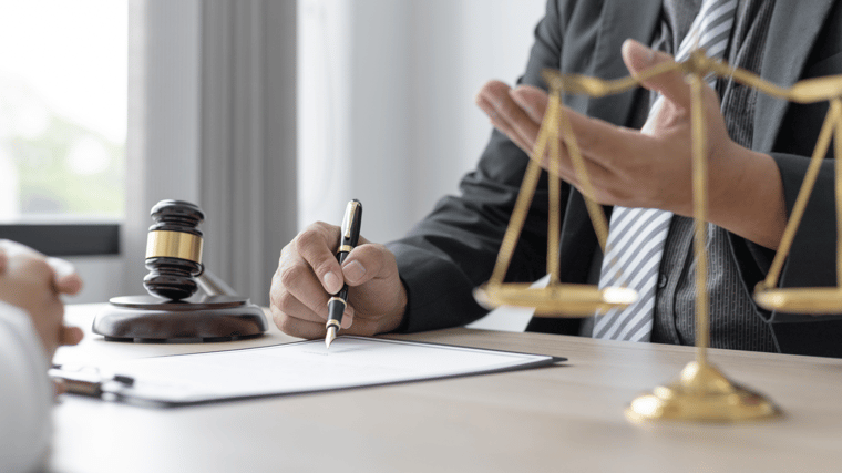 wooden gavel and lawyer hands signing a document