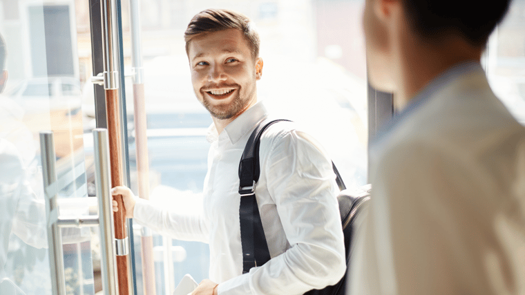 Guy walking out the door smiling back at another person