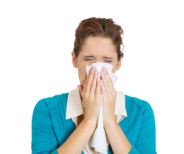 person blowing nose into tissue